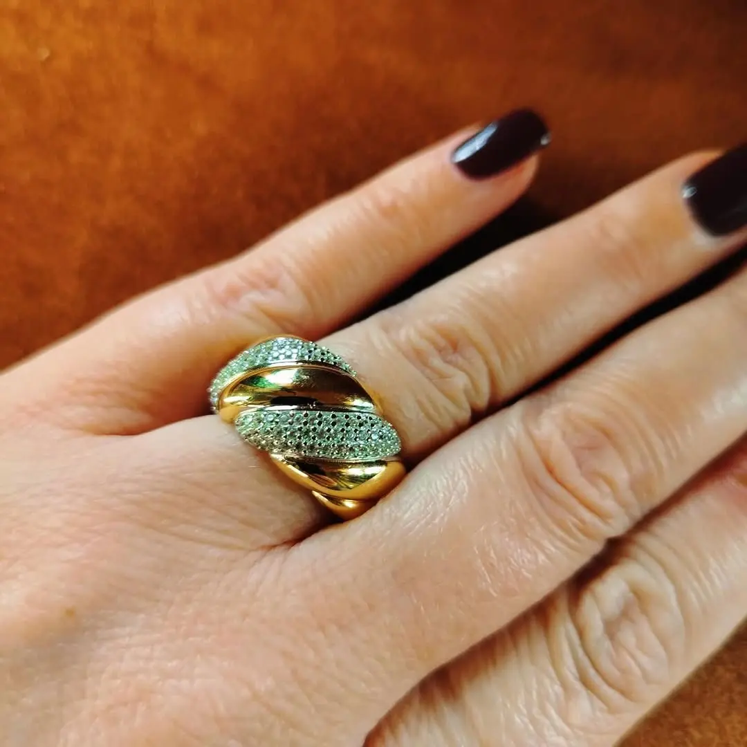 Un anello bombato in oro giallo con una fascia di zirconi verdi, indossato