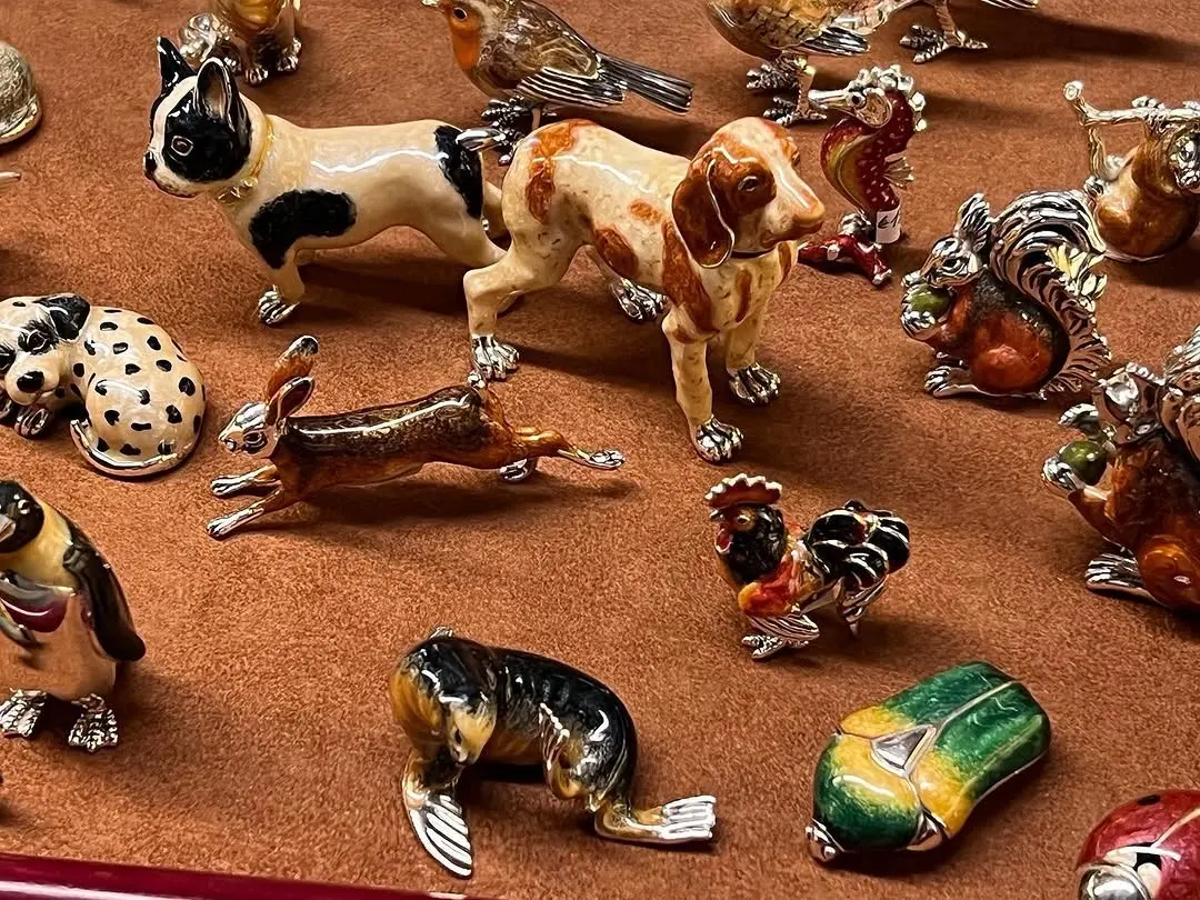 Decine di animaletti smaltati sul velluto: cani, gatti, uccelli, un orso bianco, coccinelle