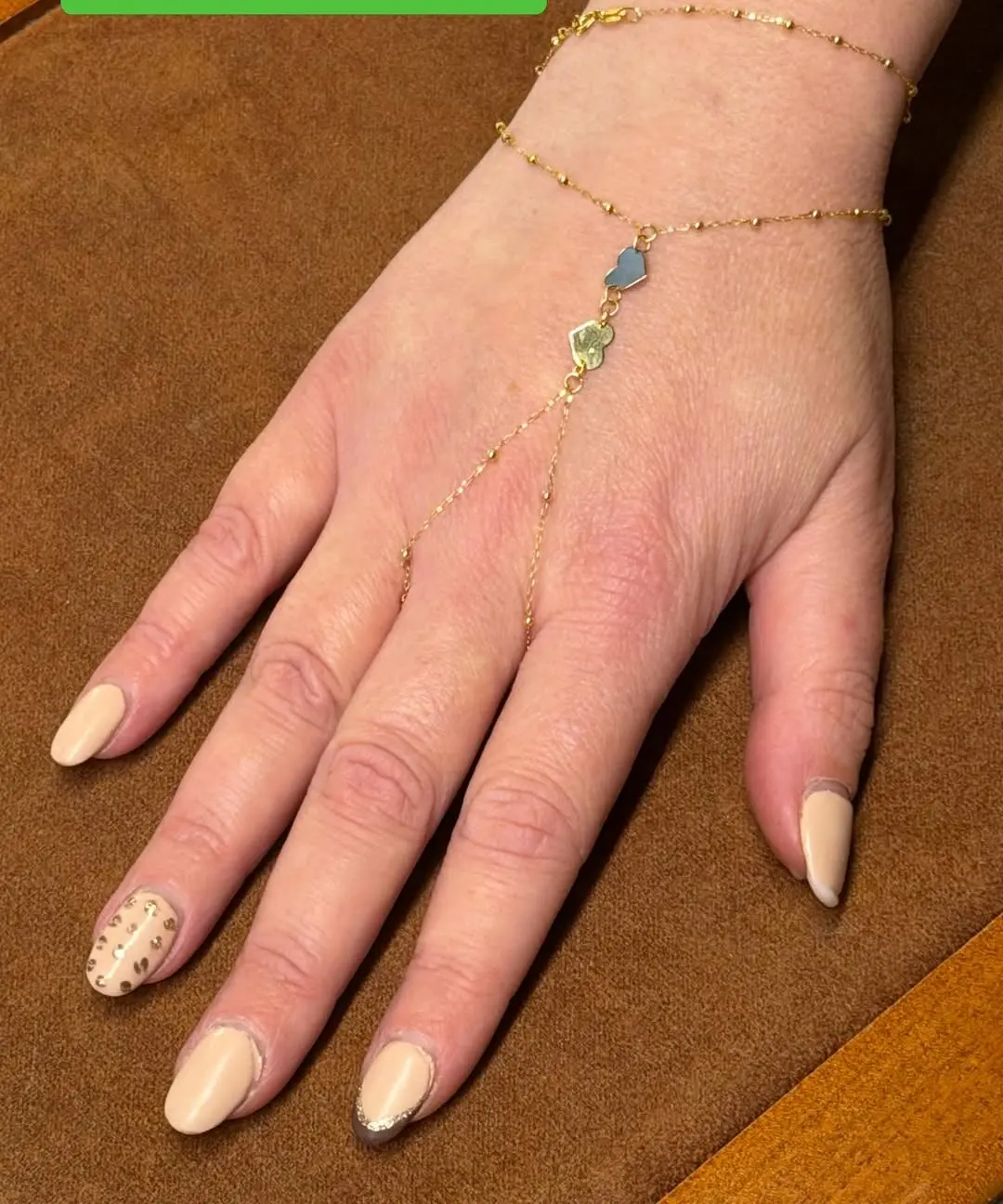 Un baciamano in oro 18 carati, catenina dal polso all'anello con una pietra azzurra, sul dorso di una mano