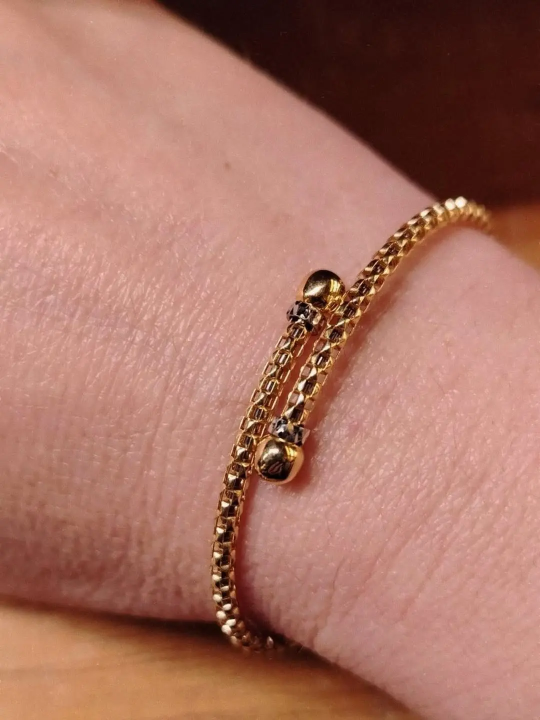 Un bracciale a spirale in maglia d'oro con le estremità a sfera, al polso
