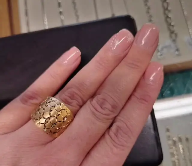 Una fascia larga in oro giallo lavorata a squame, indossata